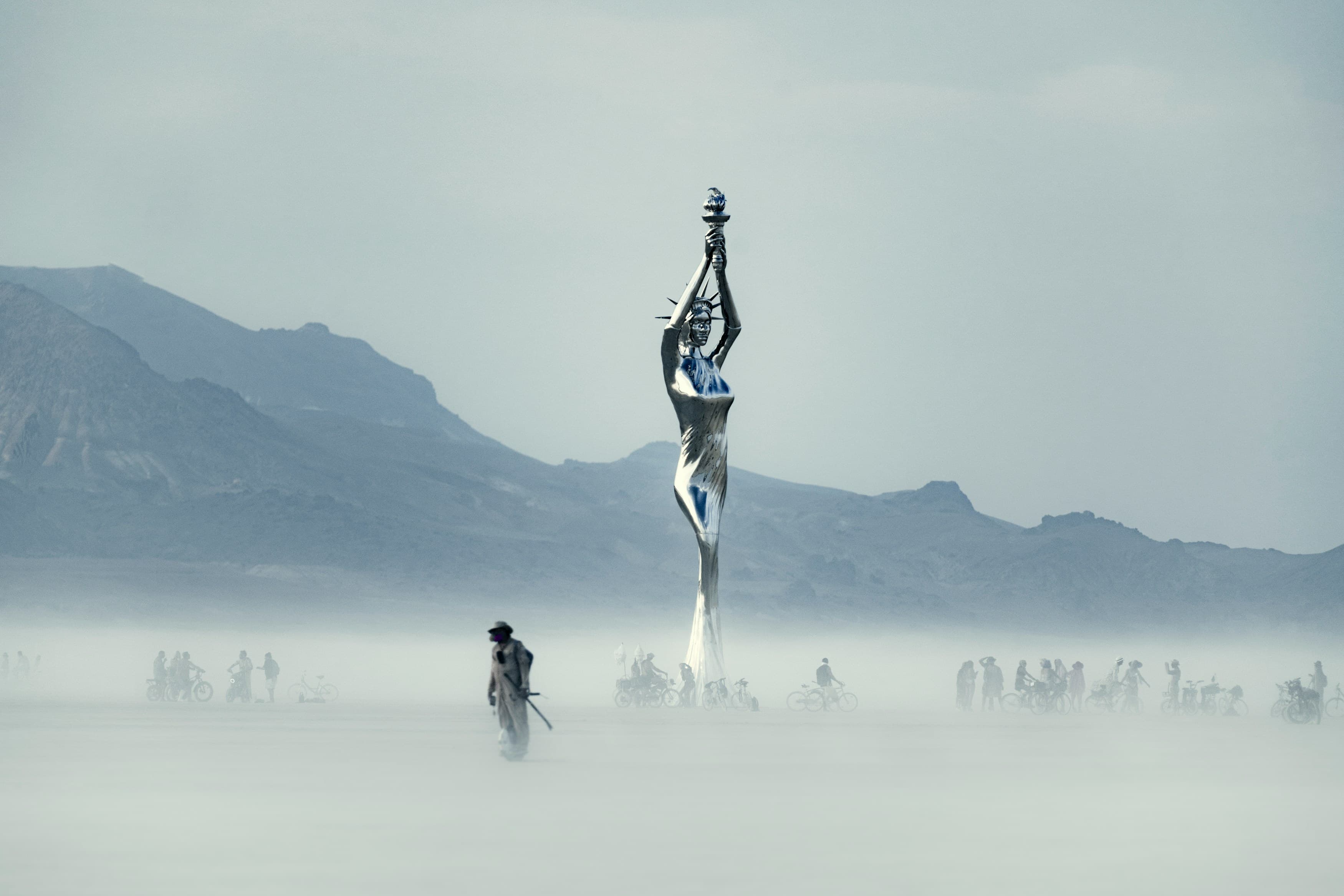 Desert landscape with a reflective sculpture and distant figures